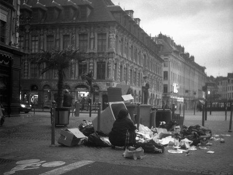 Une femme à Lille fouille les poubelles.