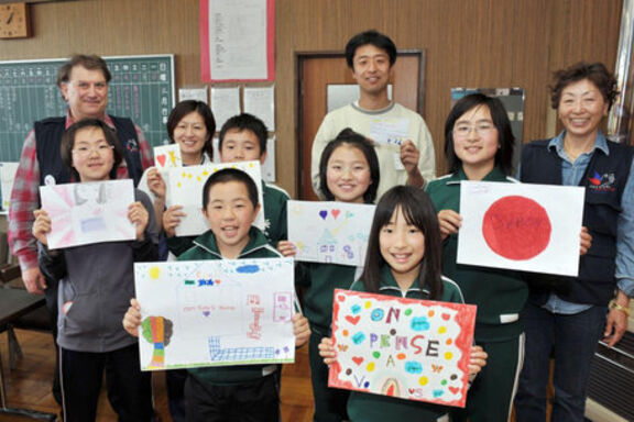 Des enfants japonais posent avec les dessins fait par les enfants de Copain du Monde, mouvement du Secours populaire.