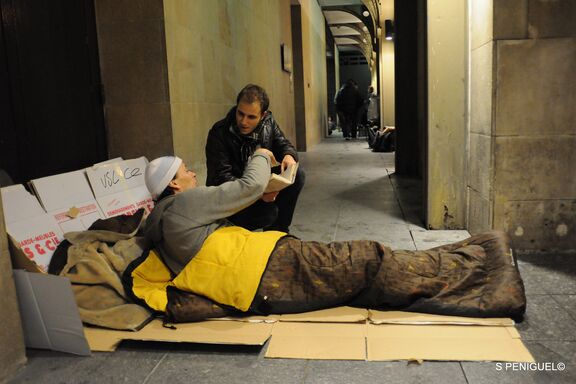 un bénévole de l'équipe de la maraude donne un livre à une personne sans-abri